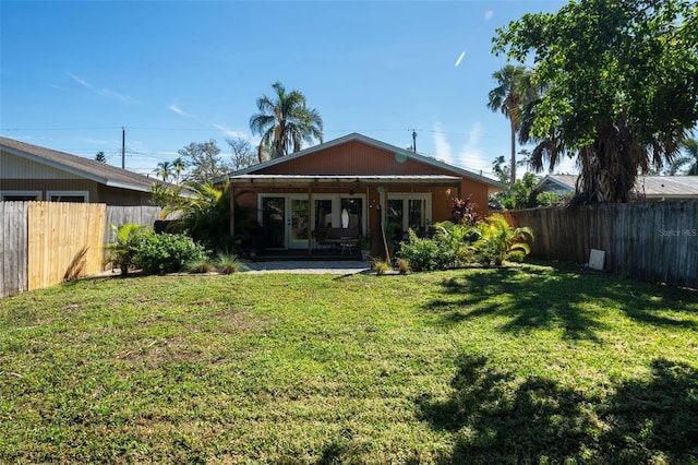 back of house featuring a lawn, french doors, and a fenced backyard