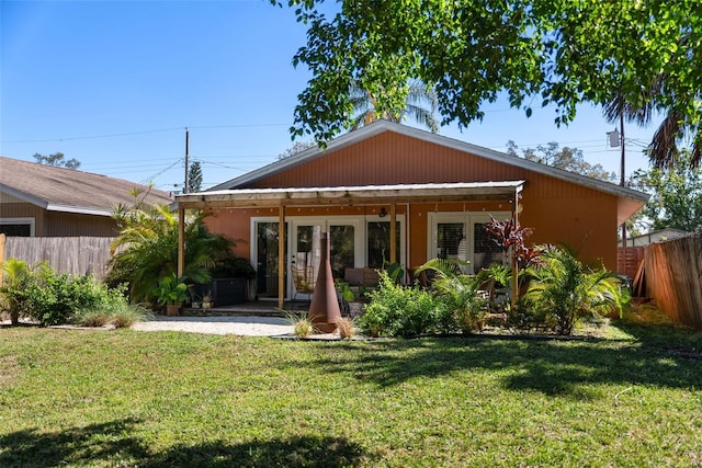 rear view of property with a patio, fence, and a lawn