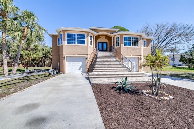 view of front of home with a garage, concrete driveway, stairs, french doors, and stucco siding