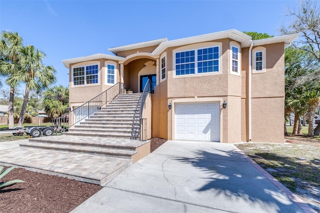 view of front facade featuring a garage, stairs, concrete driveway, and stucco siding