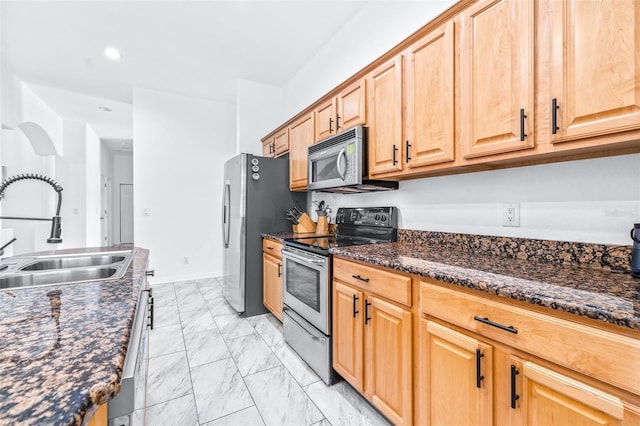 kitchen featuring marble finish floor, stainless steel appliances, recessed lighting, a sink, and dark stone countertops