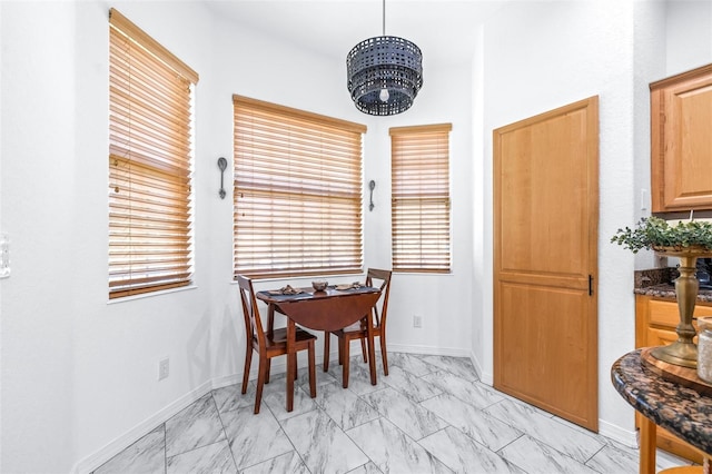 dining space with marble finish floor, baseboards, and a chandelier