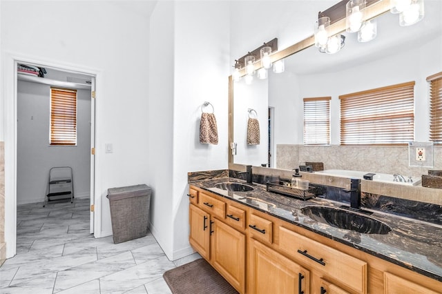 full bath with marble finish floor, double vanity, a sink, and a washtub