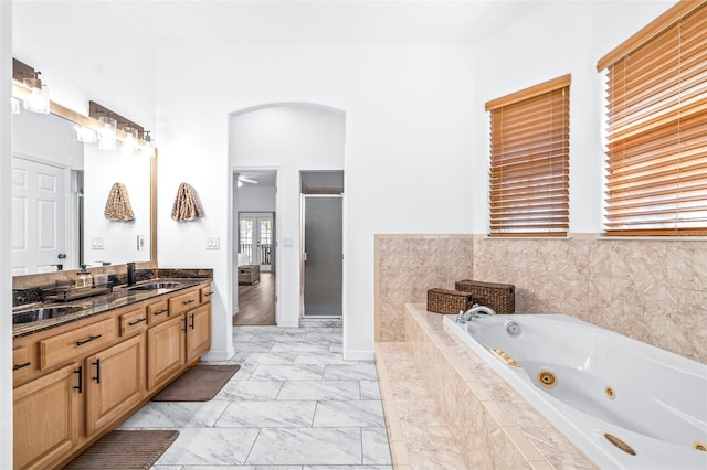 bathroom featuring marble finish floor, vanity, a shower stall, a whirlpool tub, and baseboards