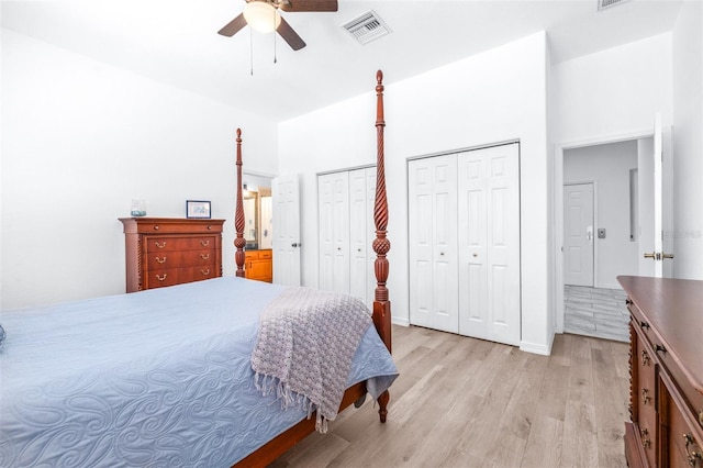 bedroom with light wood-style floors, visible vents, multiple closets, and a ceiling fan