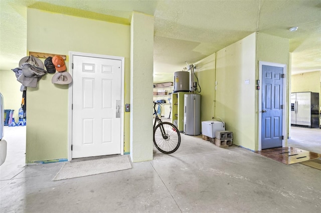 garage featuring water heater and stainless steel fridge with ice dispenser