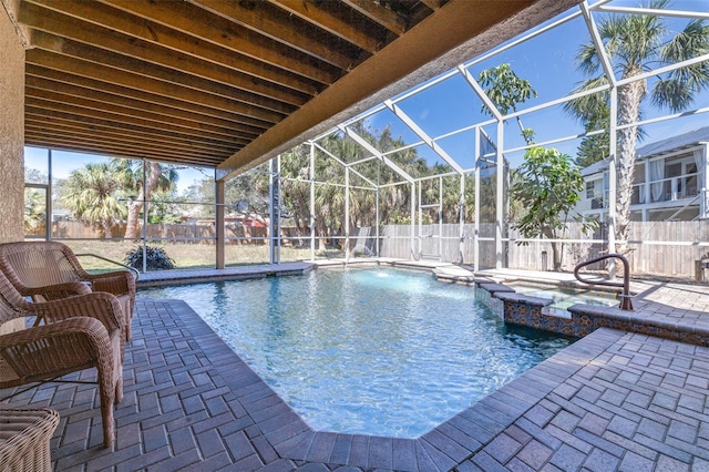 view of pool with a pool with connected hot tub, glass enclosure, a patio, and a fenced backyard