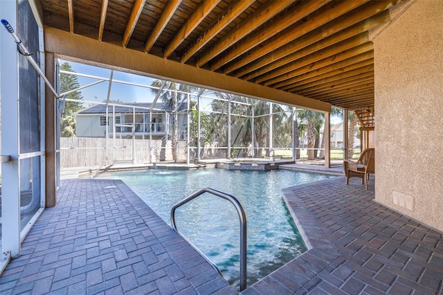 view of swimming pool featuring a patio, a pool with connected hot tub, and glass enclosure