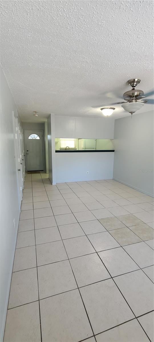 unfurnished room featuring light tile patterned floors, a textured ceiling, and a ceiling fan