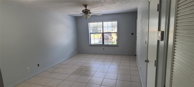 empty room featuring a textured ceiling, baseboards, a ceiling fan, and light tile patterned flooring