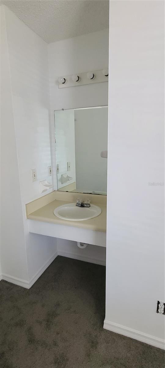 bathroom with a textured ceiling, baseboards, and a sink