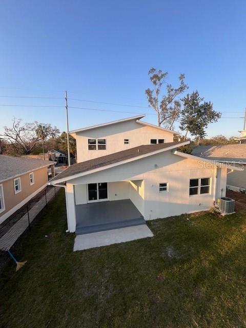 back of property featuring stucco siding, a yard, and central air condition unit