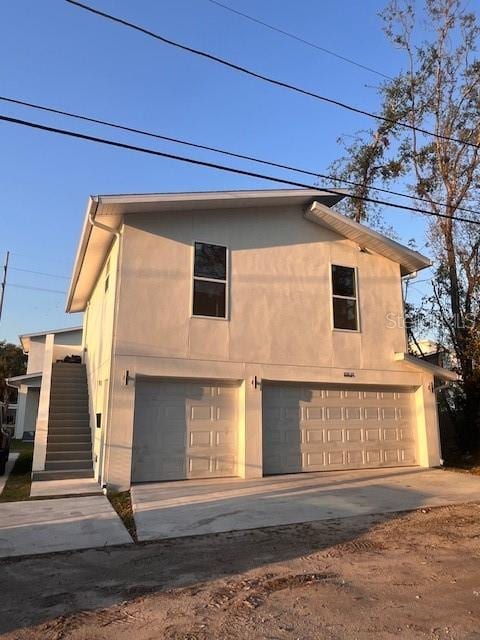 view of front of house featuring a garage, driveway, stairway, and stucco siding