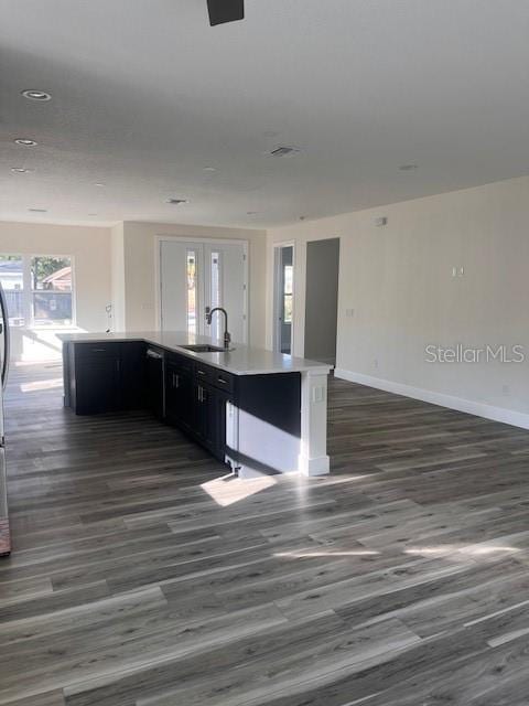 kitchen featuring dark cabinets, a sink, baseboards, open floor plan, and french doors