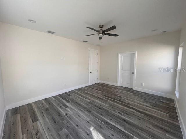 empty room featuring ceiling fan, wood finished floors, visible vents, and baseboards