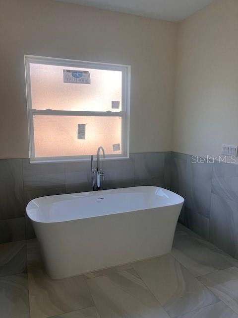 full bath featuring a freestanding tub and tile walls