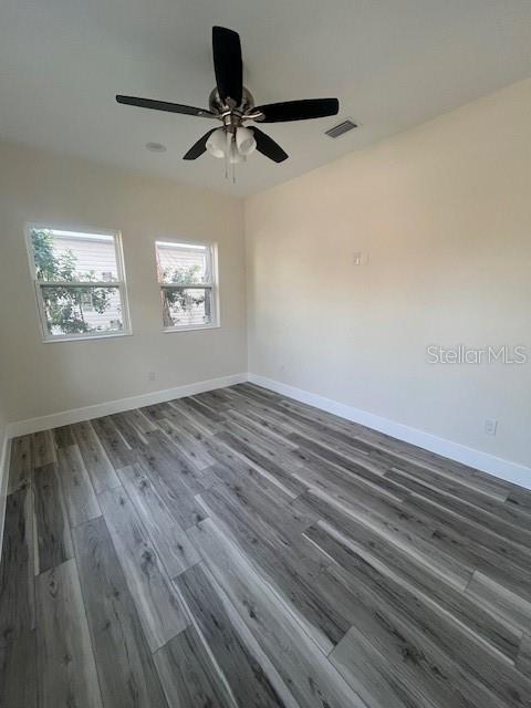 unfurnished room with wood finished floors, visible vents, and baseboards