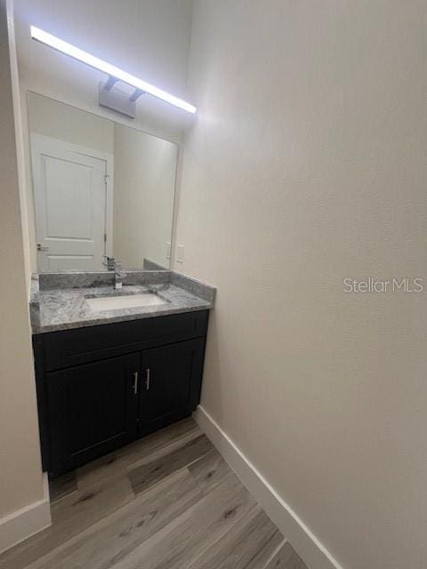 bathroom with baseboards, wood finished floors, and vanity