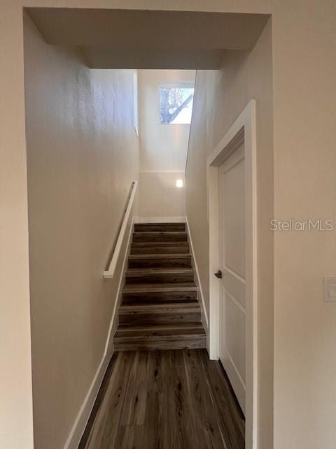 staircase featuring baseboards and wood finished floors