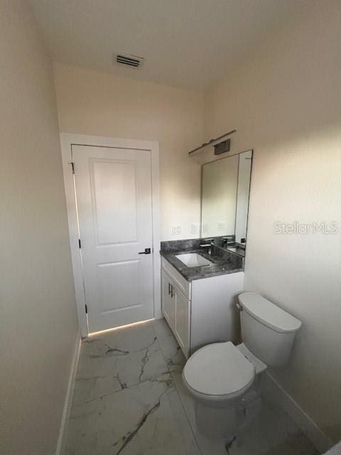 half bath with marble finish floor, vanity, toilet, and baseboards