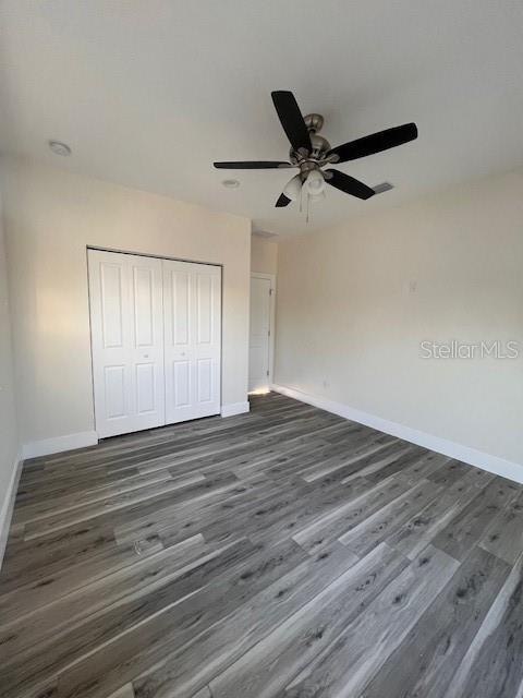 unfurnished bedroom with a closet, wood finished floors, and baseboards