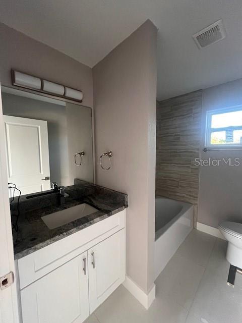 bathroom with visible vents, toilet, vanity, baseboards, and tile patterned floors