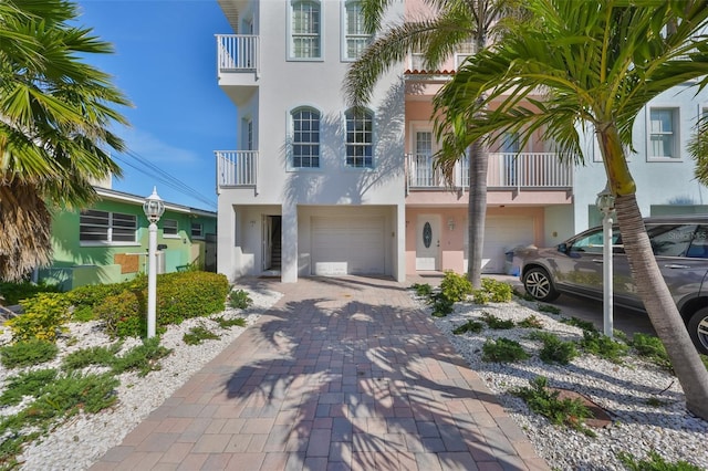 view of front of property featuring decorative driveway, an attached garage, and stucco siding