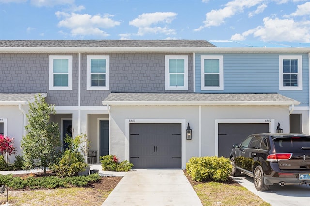 multi unit property with a garage, driveway, and stucco siding