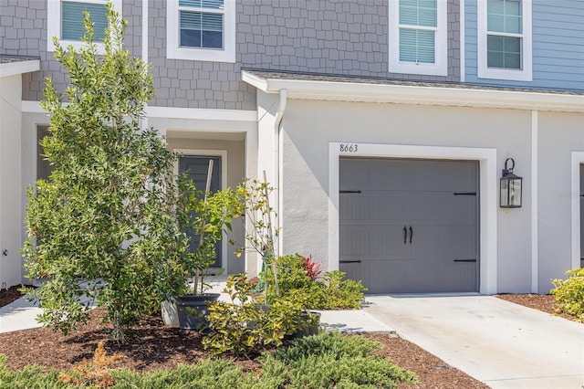 entrance to property featuring driveway, an attached garage, and stucco siding