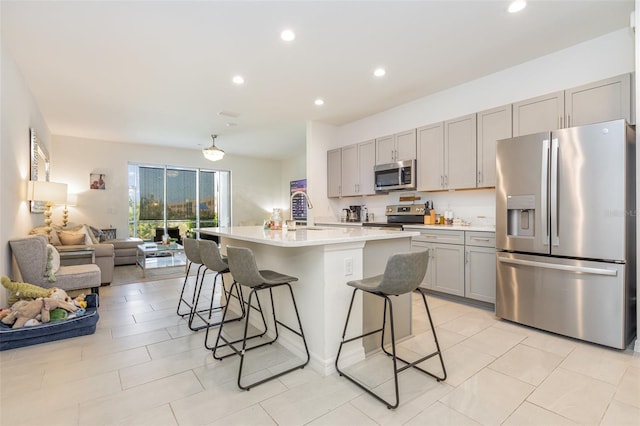 kitchen with a breakfast bar, appliances with stainless steel finishes, gray cabinets, and open floor plan