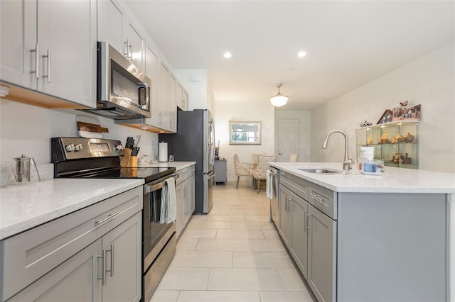 kitchen featuring a center island with sink, stainless steel appliances, gray cabinetry, a sink, and recessed lighting