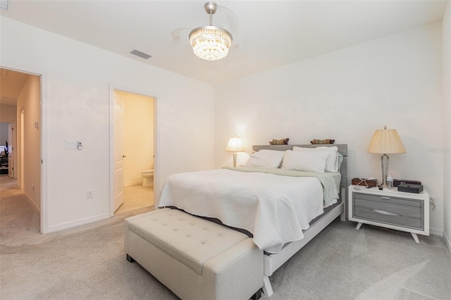 carpeted bedroom with a chandelier, ensuite bath, visible vents, and baseboards