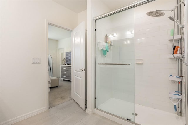 full bath featuring a stall shower, baseboards, tile patterned flooring, and ensuite bath