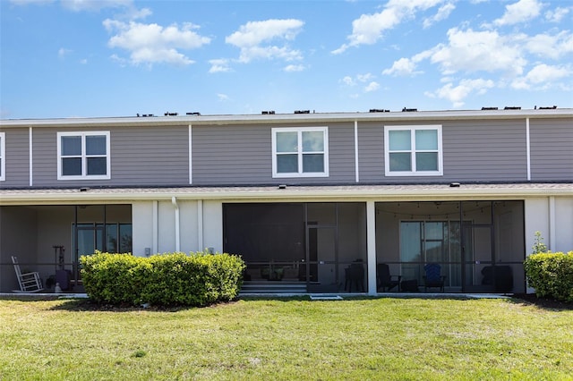 back of house featuring a lawn and a sunroom