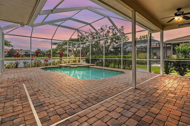 pool at dusk featuring ceiling fan, a patio, a lanai, and a pool with connected hot tub