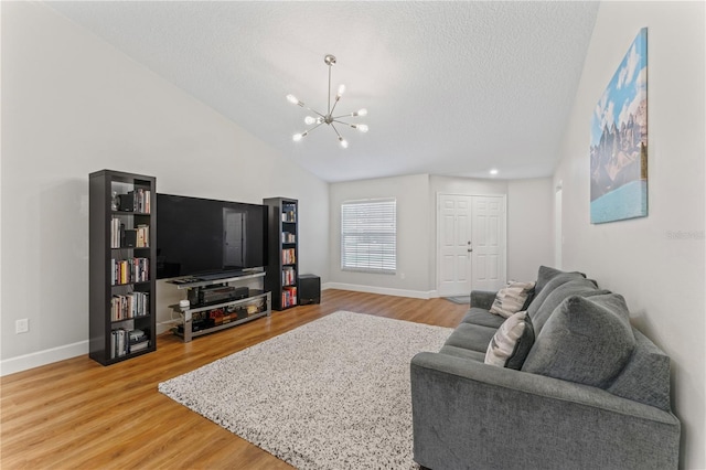 living room with light wood finished floors, baseboards, vaulted ceiling, a textured ceiling, and a chandelier