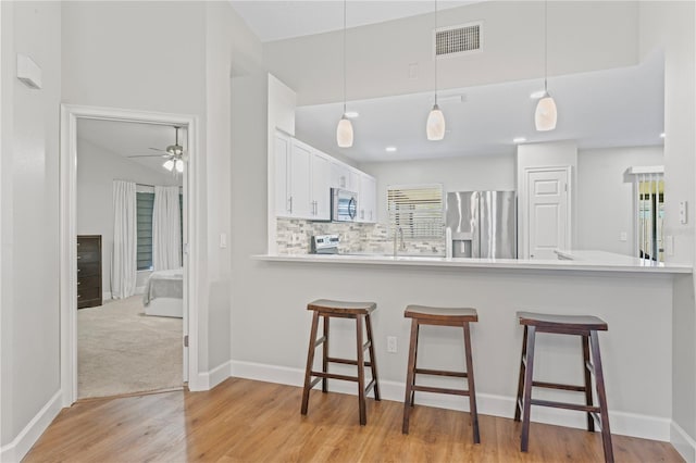 kitchen with a peninsula, appliances with stainless steel finishes, a breakfast bar, and decorative backsplash