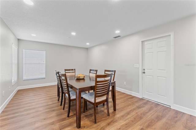 dining area featuring visible vents, light wood-style flooring, and baseboards