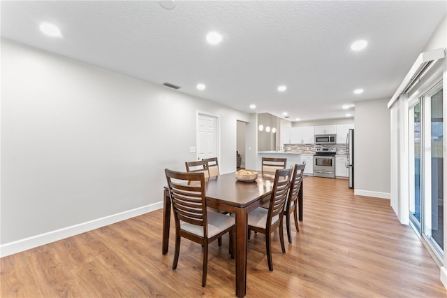 dining room featuring baseboards, visible vents, and light wood finished floors