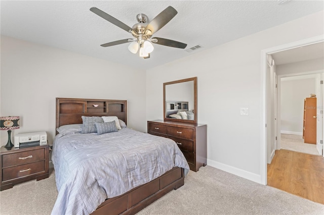 bedroom featuring a textured ceiling, a ceiling fan, visible vents, and baseboards