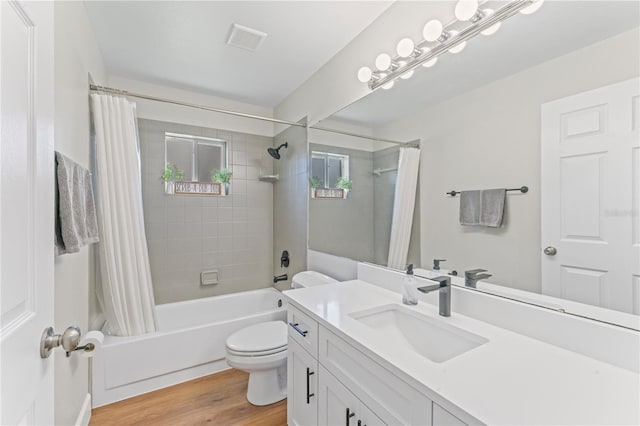 full bath featuring toilet, wood finished floors, vanity, visible vents, and shower / bath combo