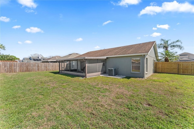 back of property with a yard, a fenced backyard, a sunroom, and stucco siding