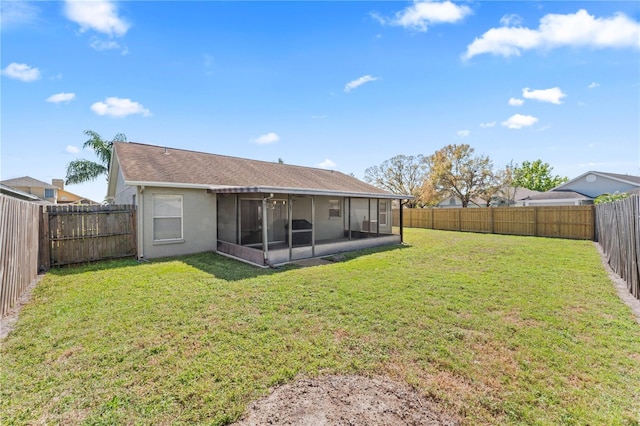 rear view of house with a sunroom, a fenced backyard, a lawn, and stucco siding