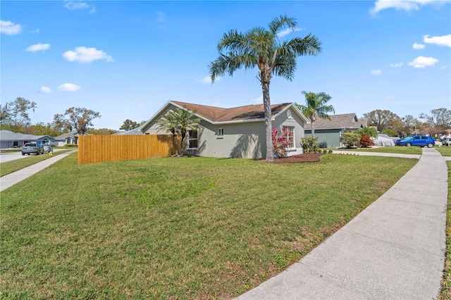 view of front of house featuring fence, a front lawn, and stucco siding