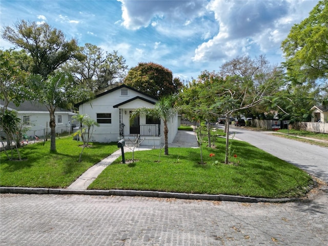 bungalow-style house with driveway, a front lawn, and fence