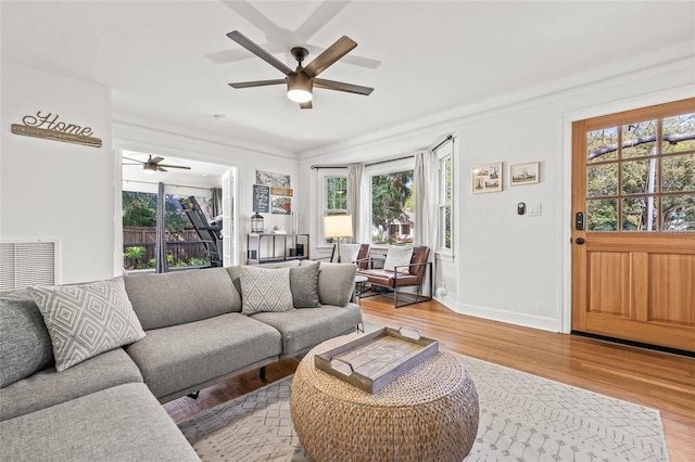 living area with light wood-style floors, a healthy amount of sunlight, baseboards, and a ceiling fan