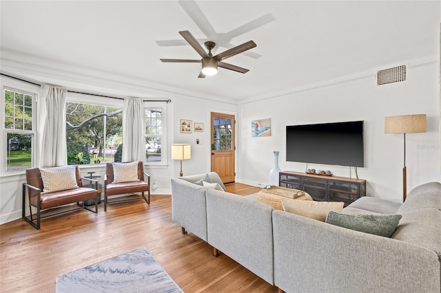 living area featuring a ceiling fan, baseboards, visible vents, and light wood finished floors