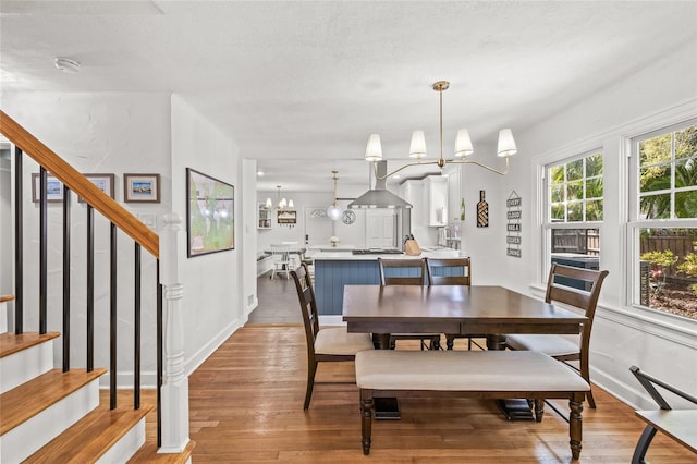 dining area with a chandelier, wood finished floors, a textured ceiling, and stairs