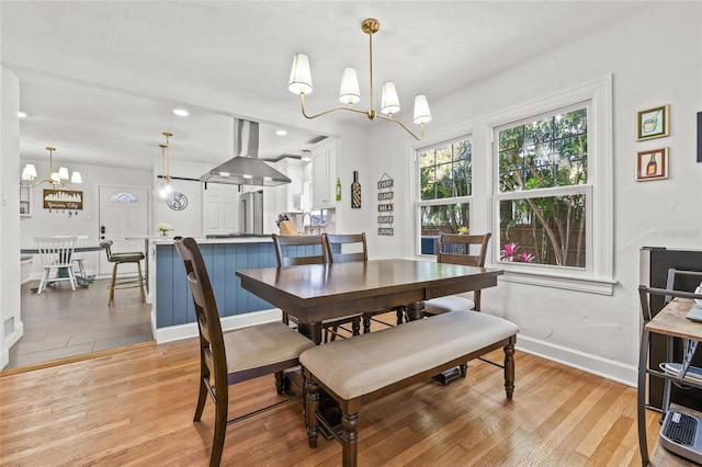 dining area with a chandelier, light wood-style flooring, and baseboards