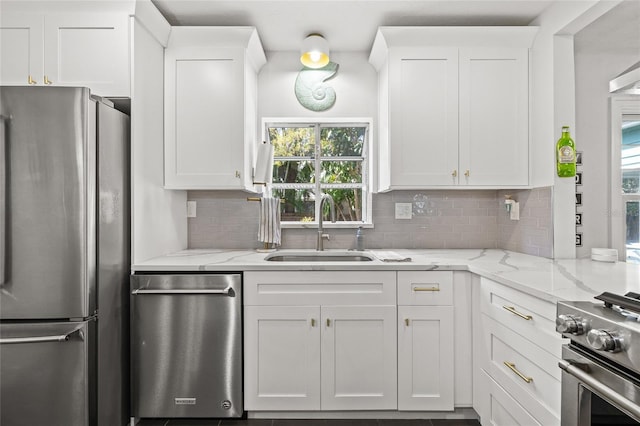 kitchen with appliances with stainless steel finishes, white cabinets, a sink, and decorative backsplash